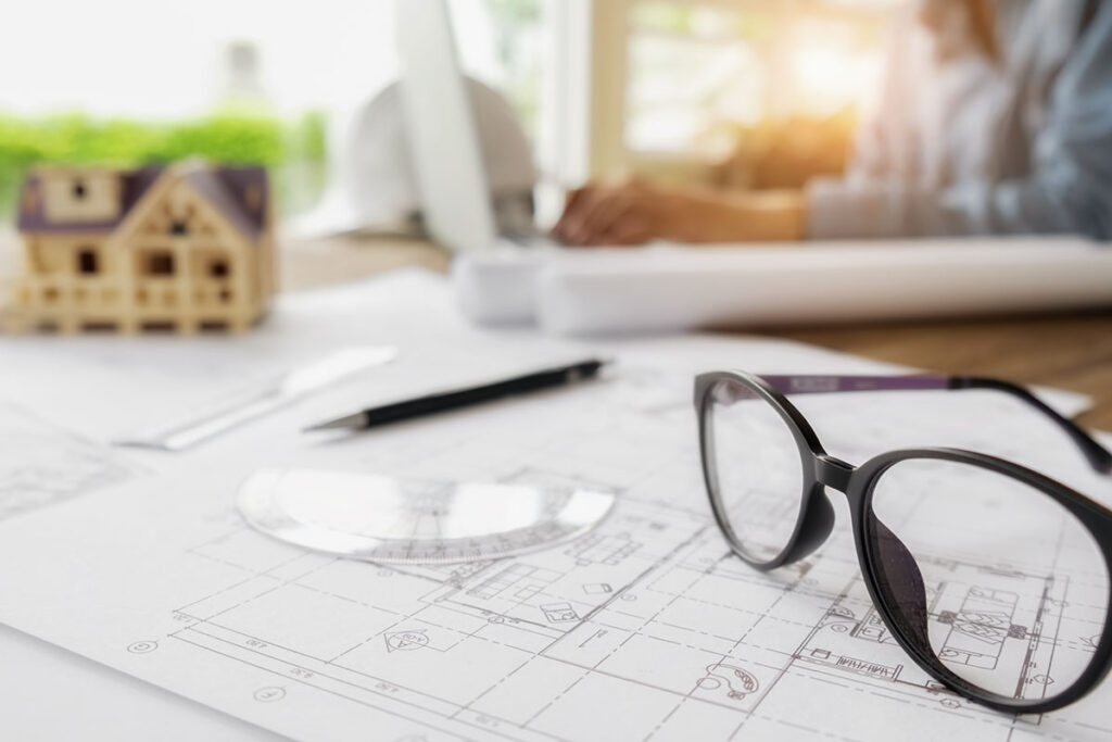 Architekturpläne, Brille, Hausmodell, Sonnenlicht.